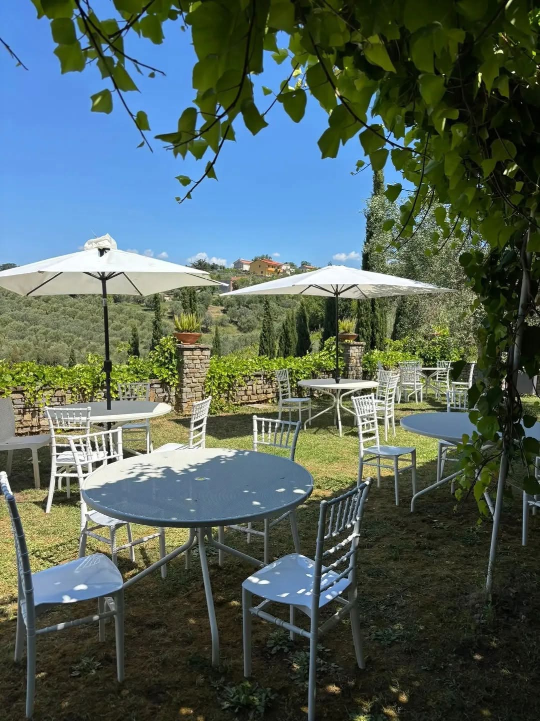 Tavoli rotondi apparecchiati in giardino sotto gli ombrelloni